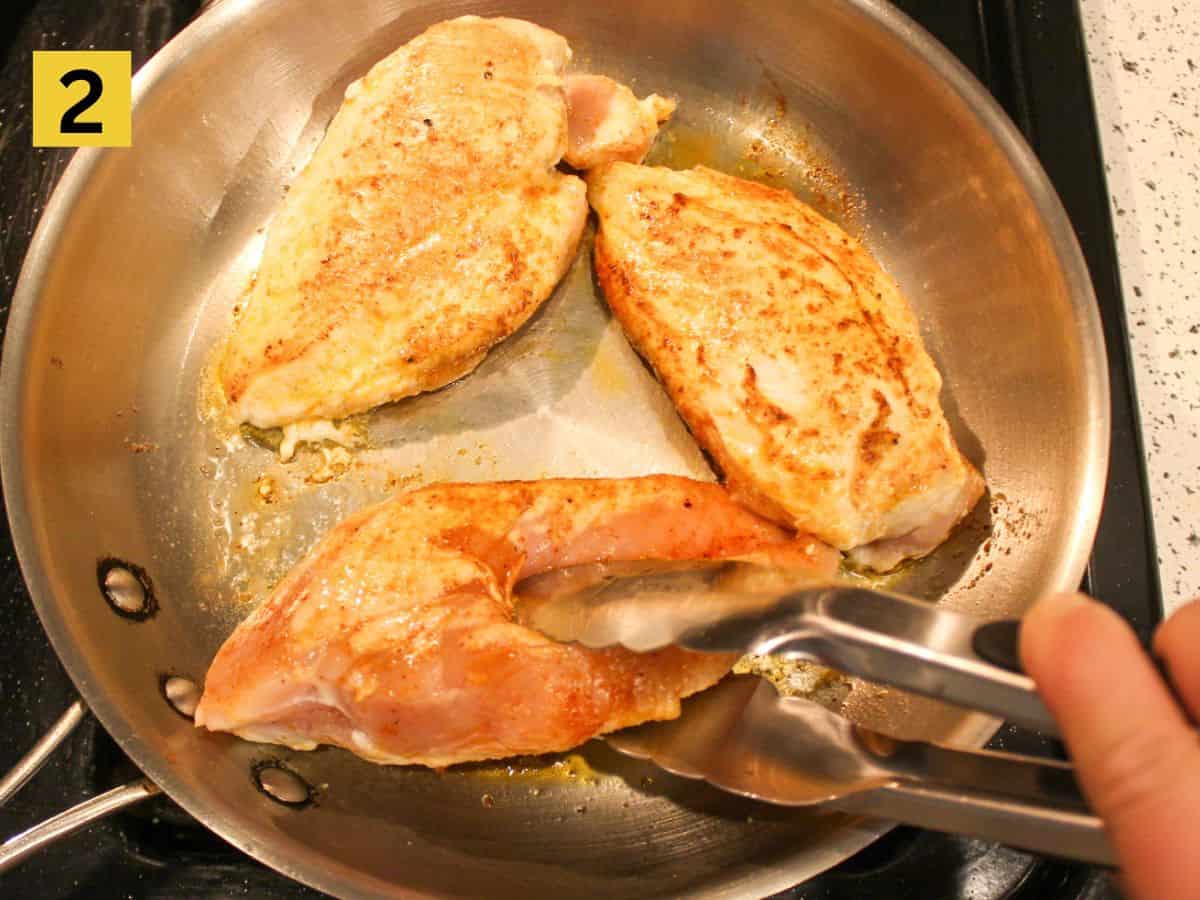 Searing the chicken in a stainless steel skillet.