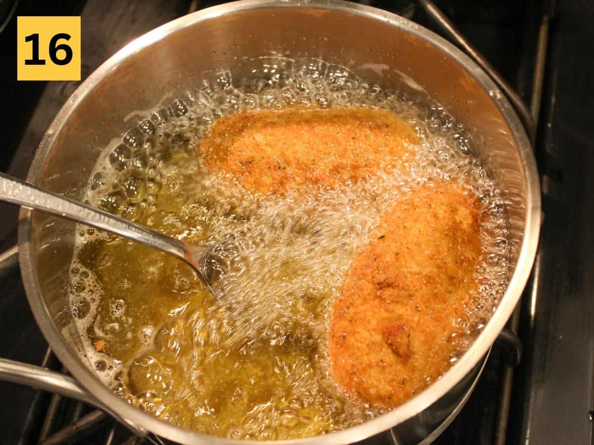 Golden brown chicken Kyiv cutlets frying in oil in a stainless steel pot.