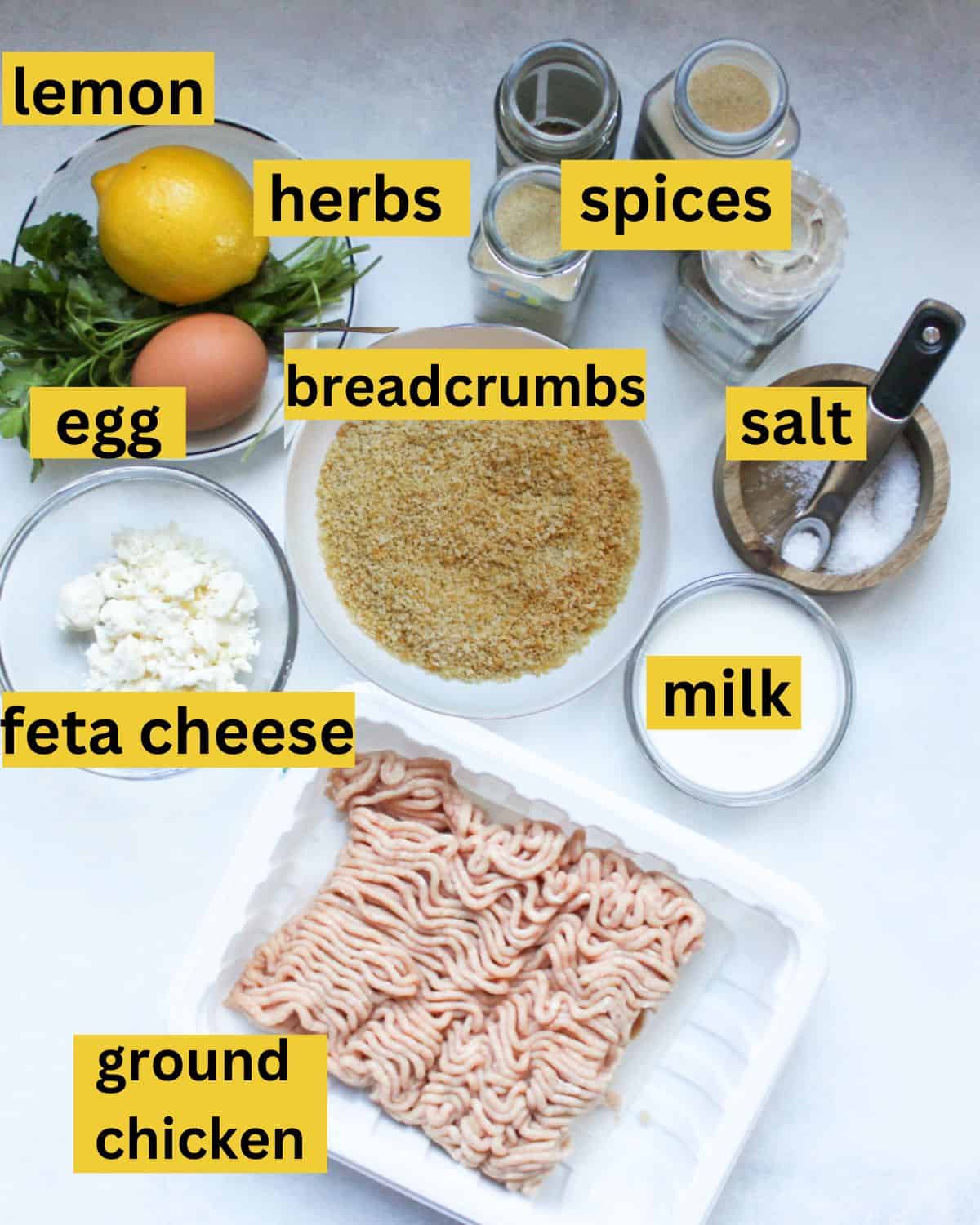 Recipe ingredients on a white background labeled as hers, spices, egg, breadcrumbs, salt, feta cheese, milk ground chicken.