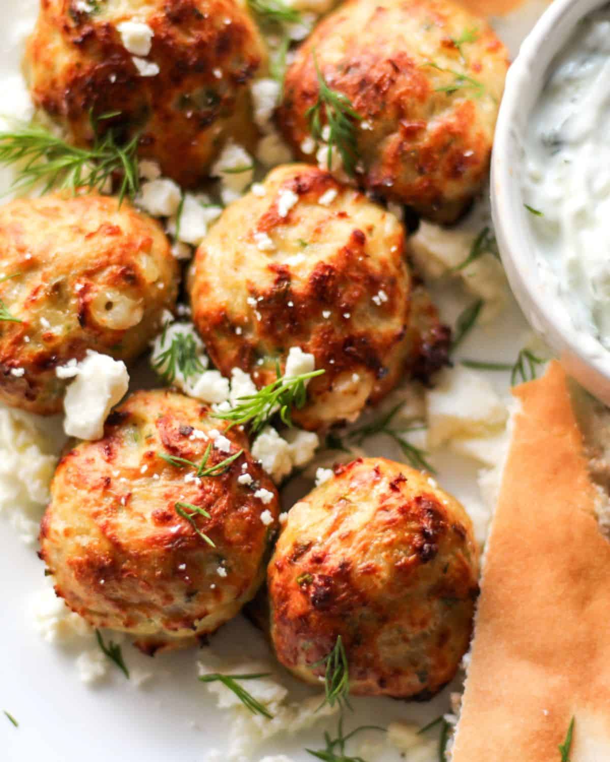 Browned chicken meatballs sprinkled with crumbled feta cheese and fresh chopped dill on top.