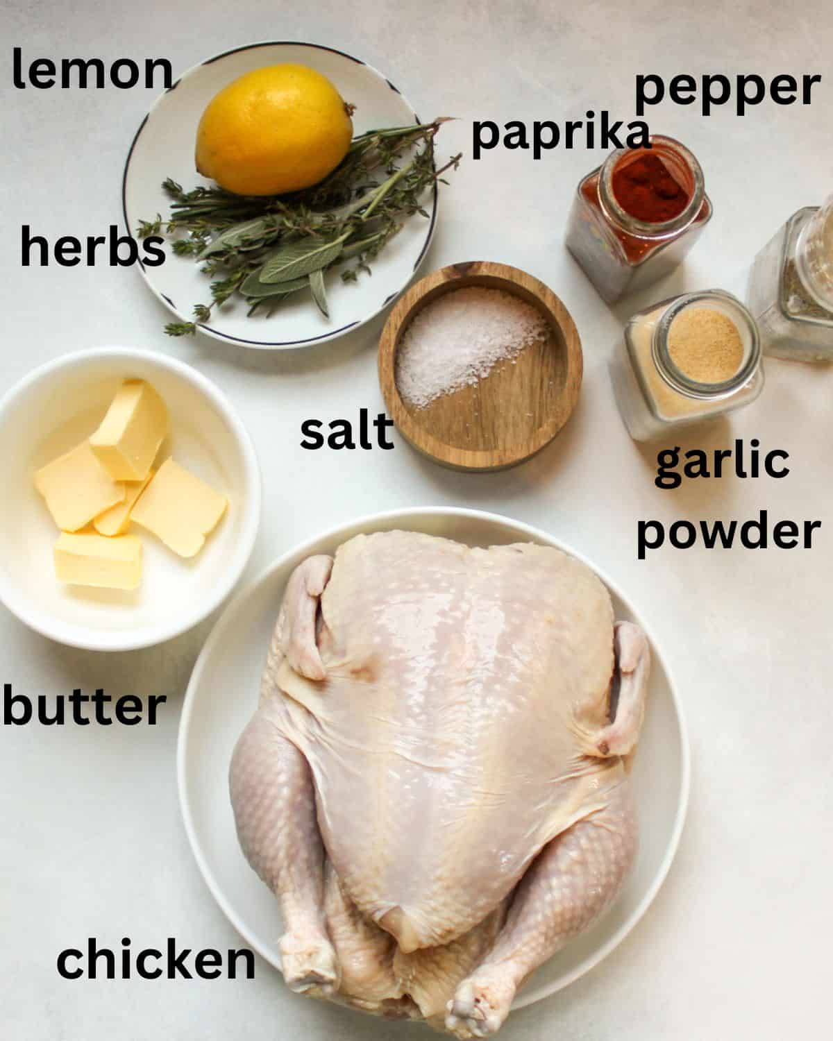 Recipe ingredients on a white background labeled as lemon hers, butter, chicken, paprika, salt, pepper, garlic powder.