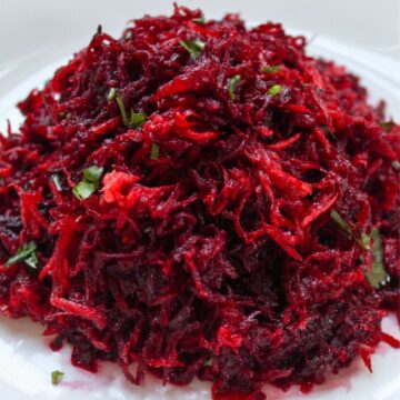 Grated raw beet salad on a white dish.