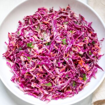 Purple cabbage coleslaw in a white dish.