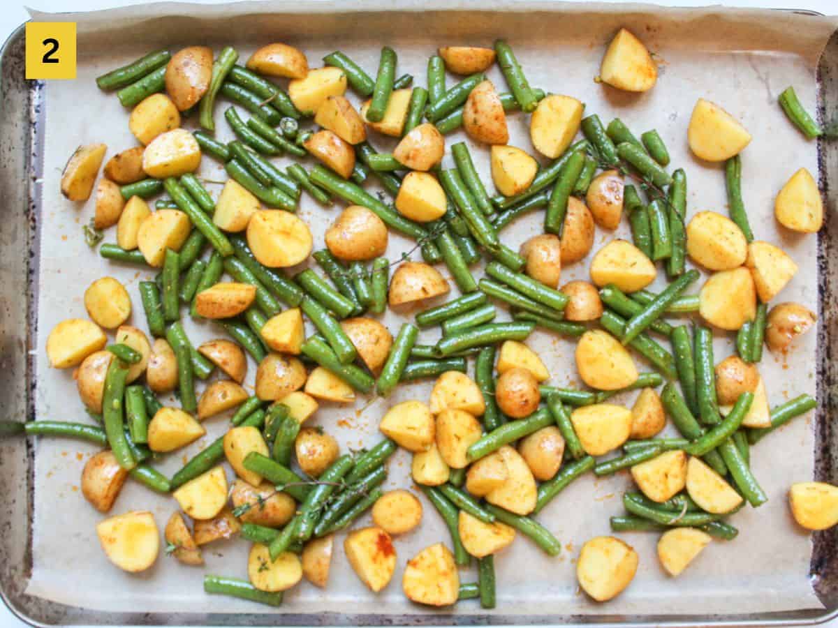 Seasoned vegetables arranged in a single layer on a baking sheet pan lined with parchment paper.