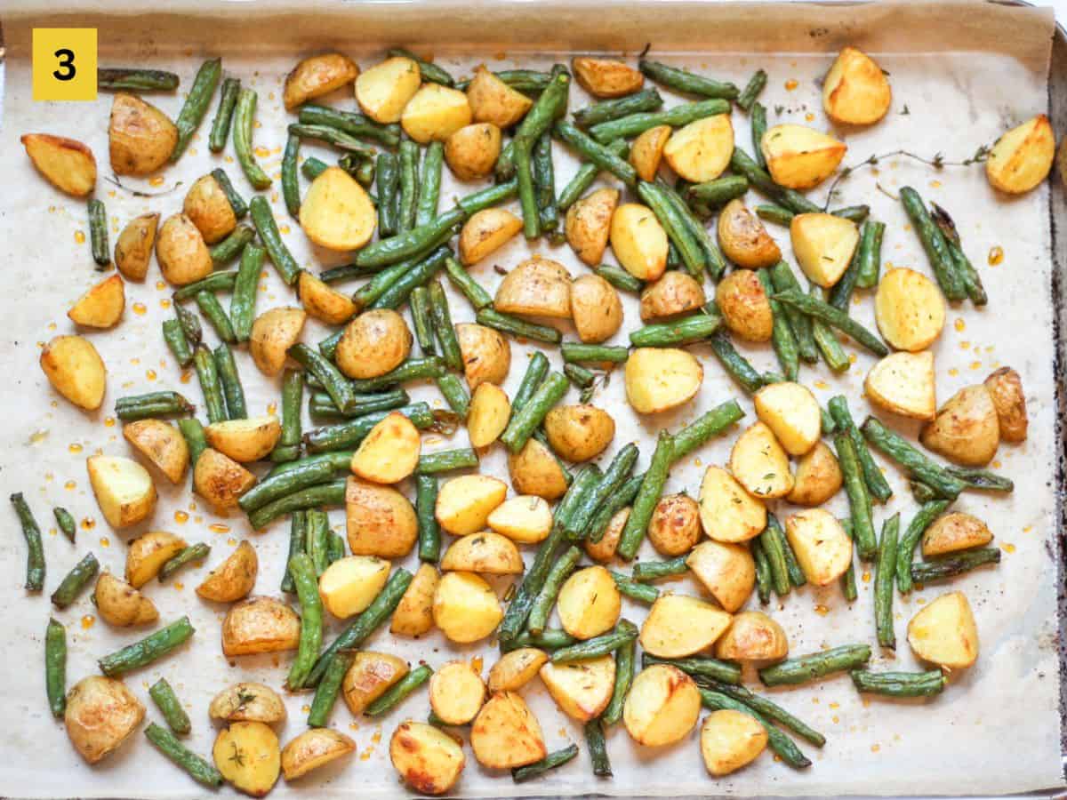 Roasted crispy potatoes and string beans on a baking pan.
