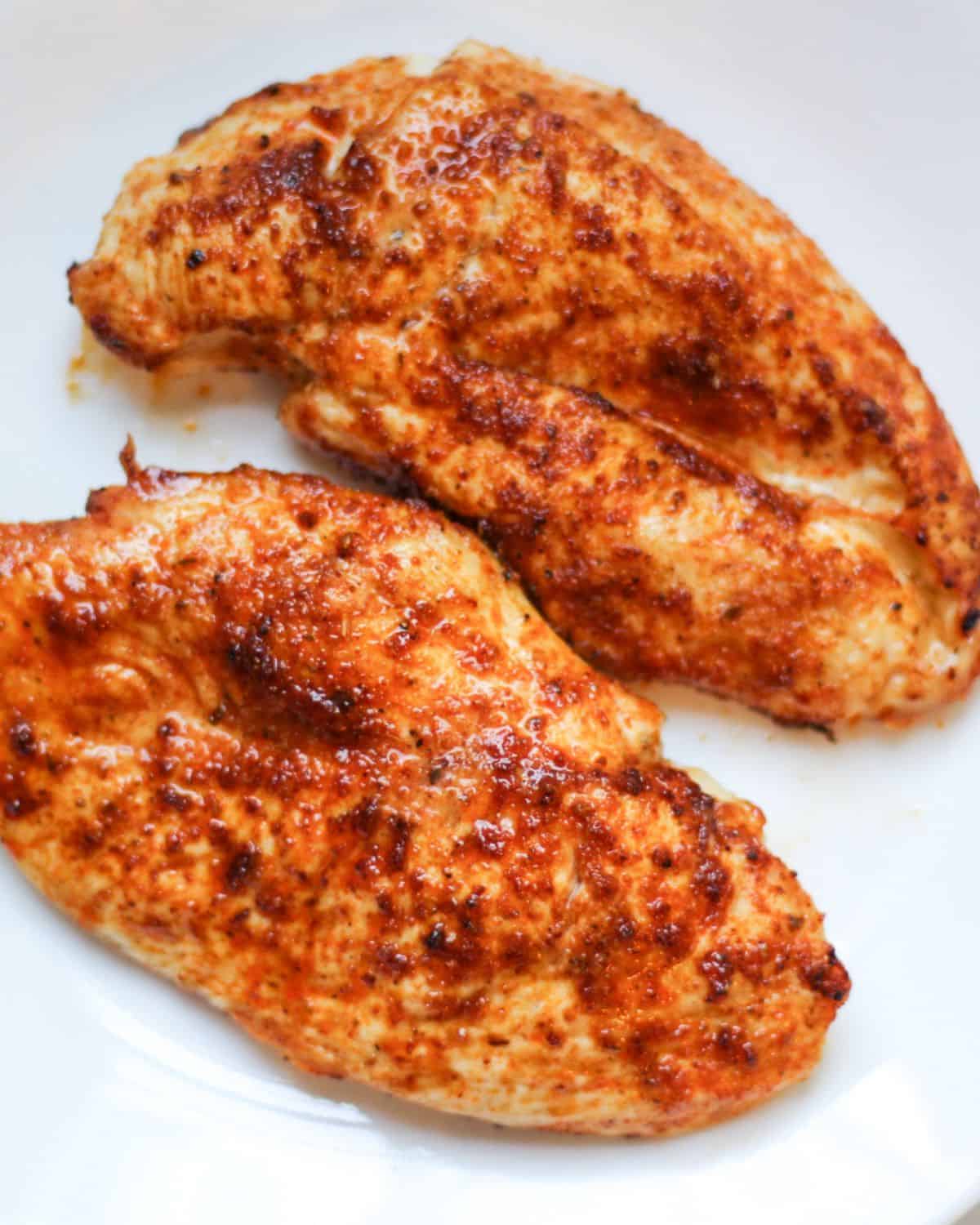 Air fried thin chicken breasts on a white plate. 