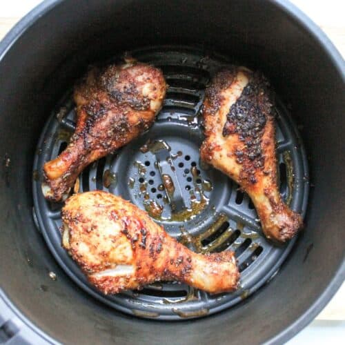 Crispy, golden-brown air fryer chicken drumsticks in the air fryer basket, ready to serve.