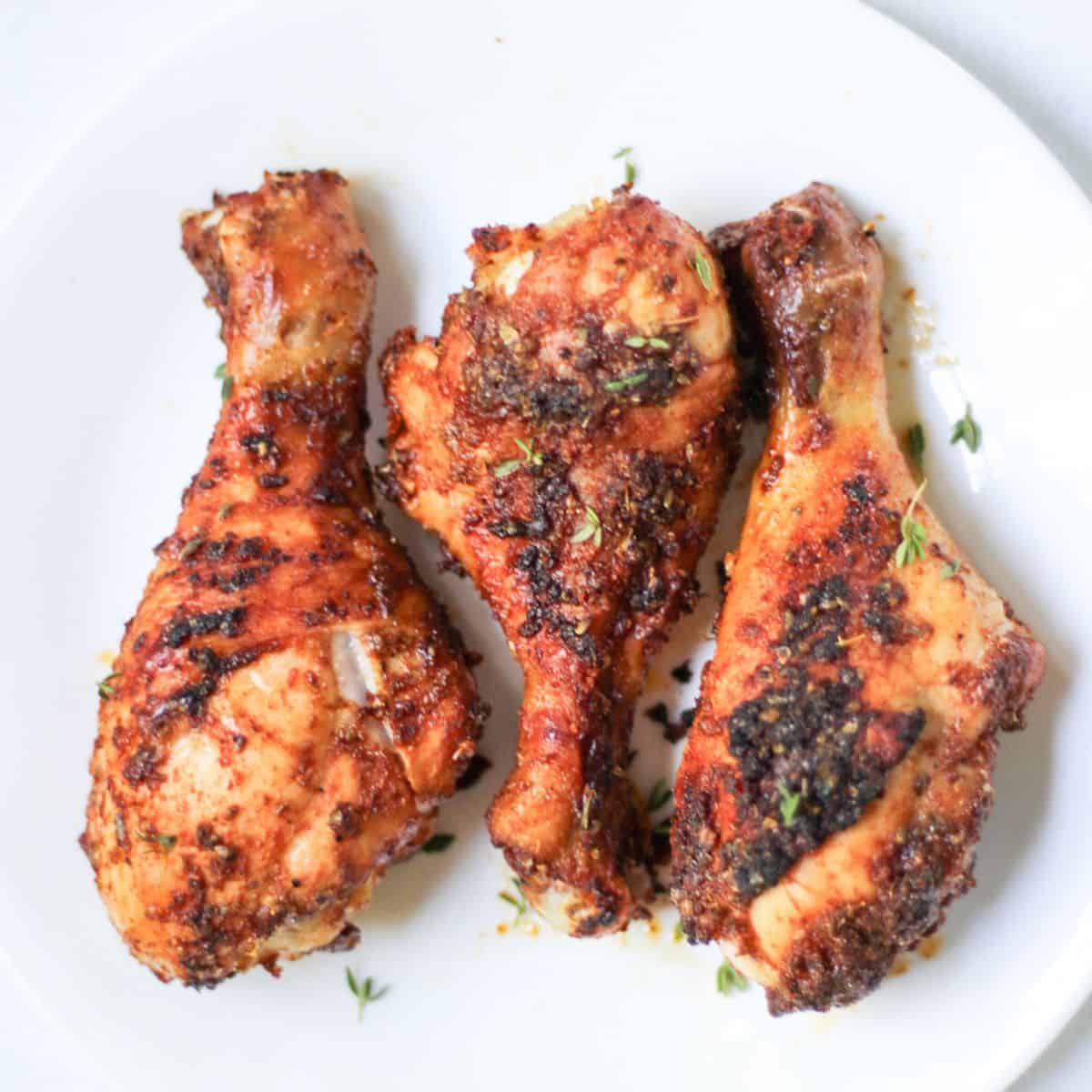 Air fryer chicken drumsticks with crispy skin served on a white plate.