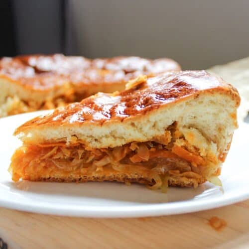 A slice of savory pie with cabbage filling served on a white plate.