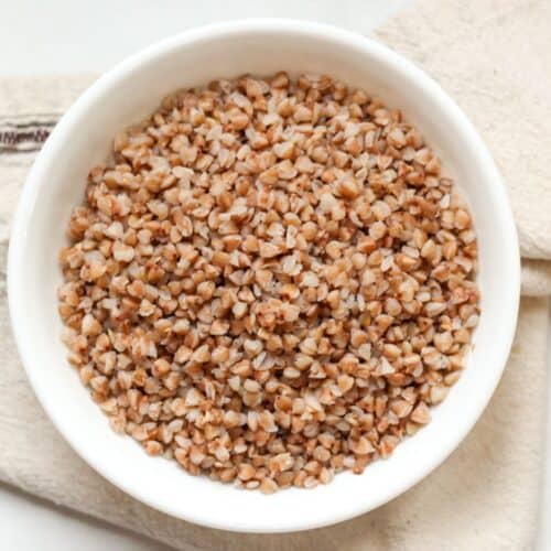 Fluffy buckwheat served in a white ceramic bowl on a tan kitchen napkin.