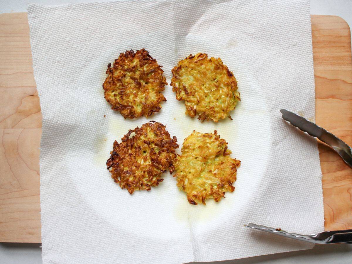 Freshly fried cabbage fritters are placed on a paper towel to absorb oil.