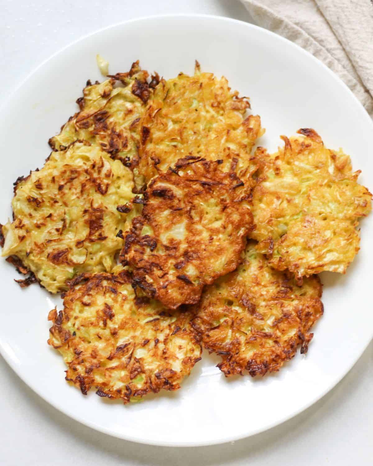 Crispy cabbage fritters neatly arranged on a white plate.