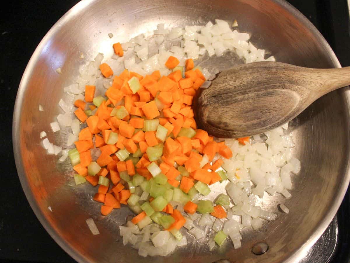Cooking step: diced onions, carrots and celery added to the skillet with melted butter.