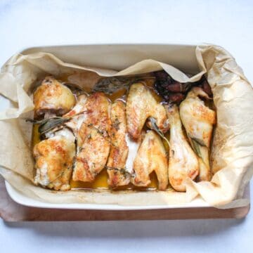 Juicy roasted chicken pieces in a large baking pan.