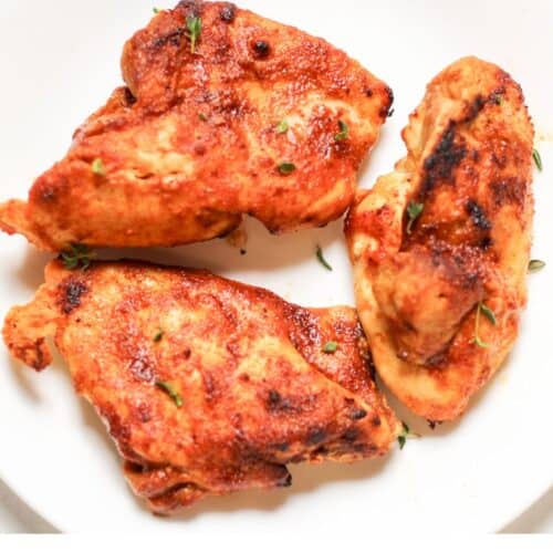 Air fried from frozen chicken thighs are ready to be served on a white plate.