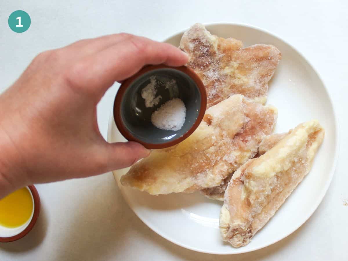 Seasoning frozen chicken thighs with salt.