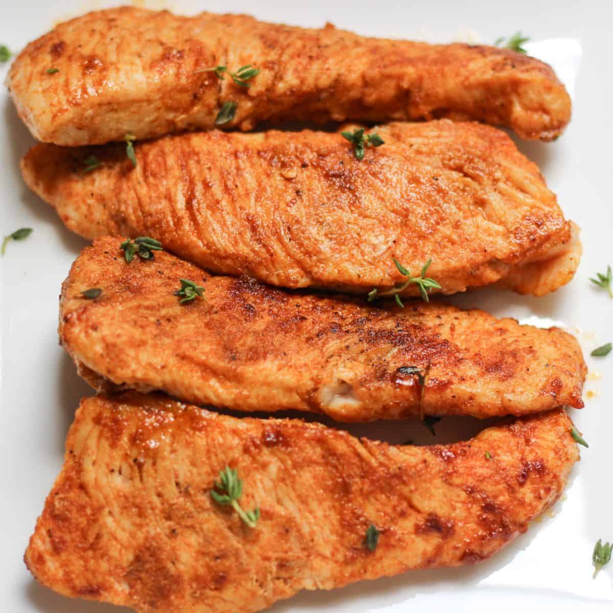 Juicy turkey steaks served on a white plate.
