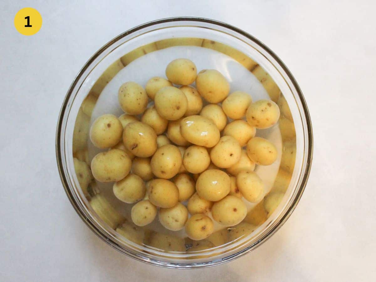 Washing baby potatoes in a bowl filled with water.