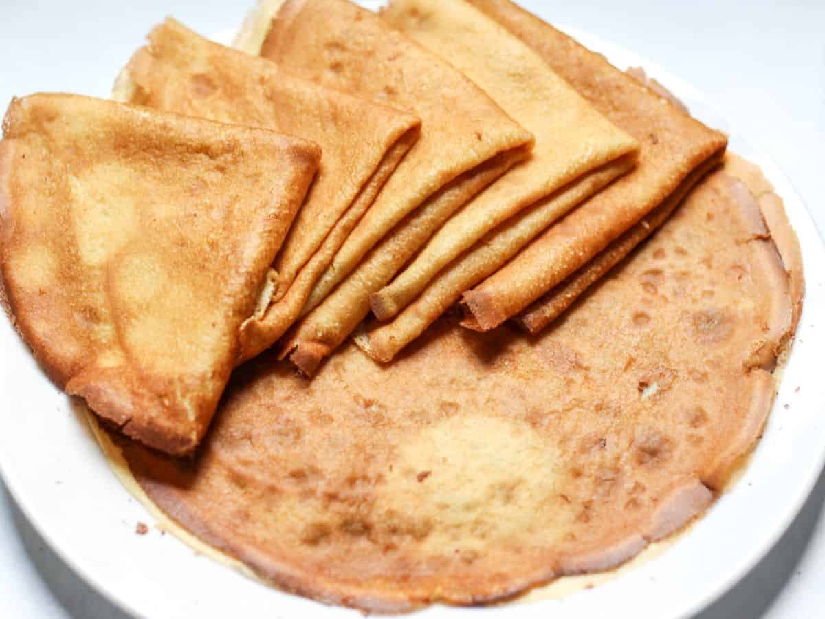 Crepes served on a plate folded in to triangles. 