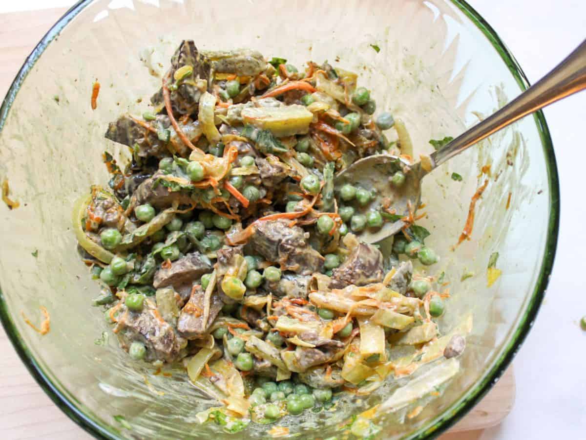 Mixing chicken liver salad in a bowl.