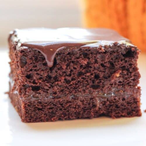 Slice of chocolate snack cake with jam filling and glossy chocolate glaze on top.