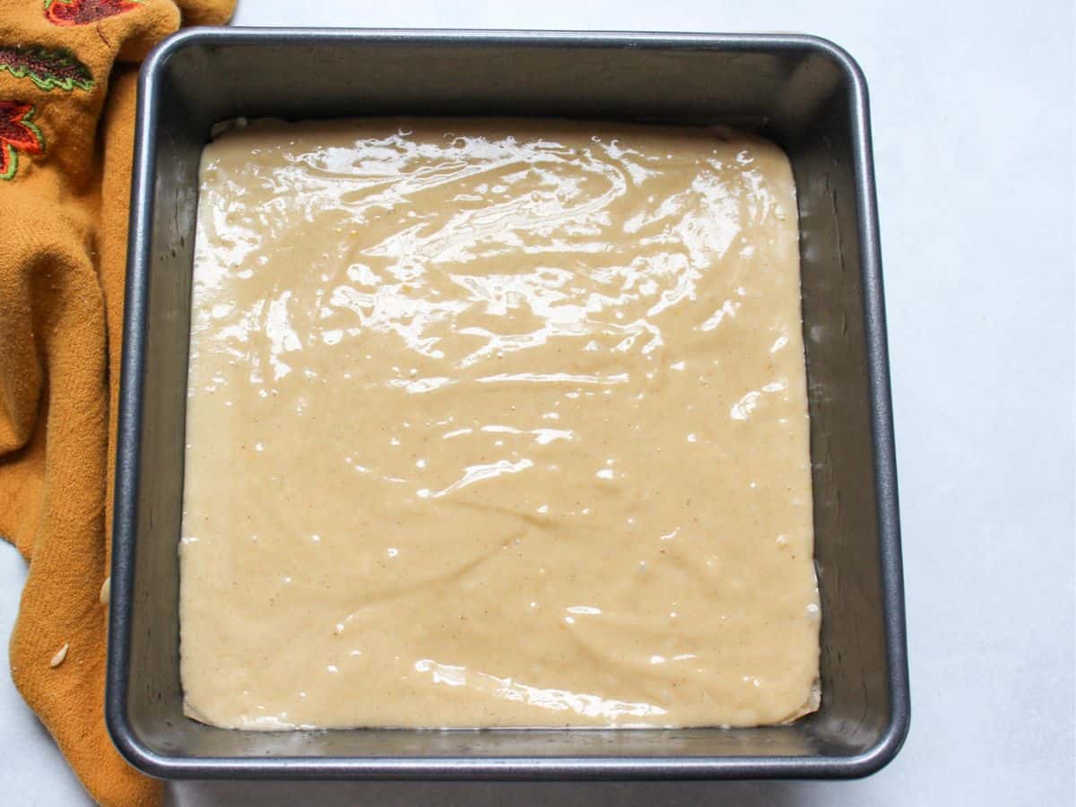 Honey cake batter poured into a square baking pan before going into the oven.