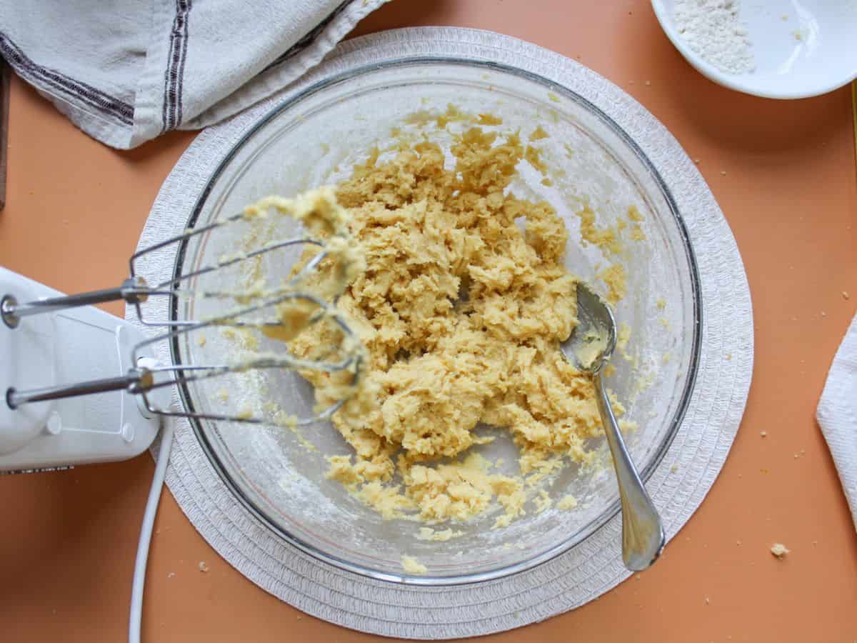 Prepared orange cookie batter in a large glass bowl, ready to be refrigerated. 