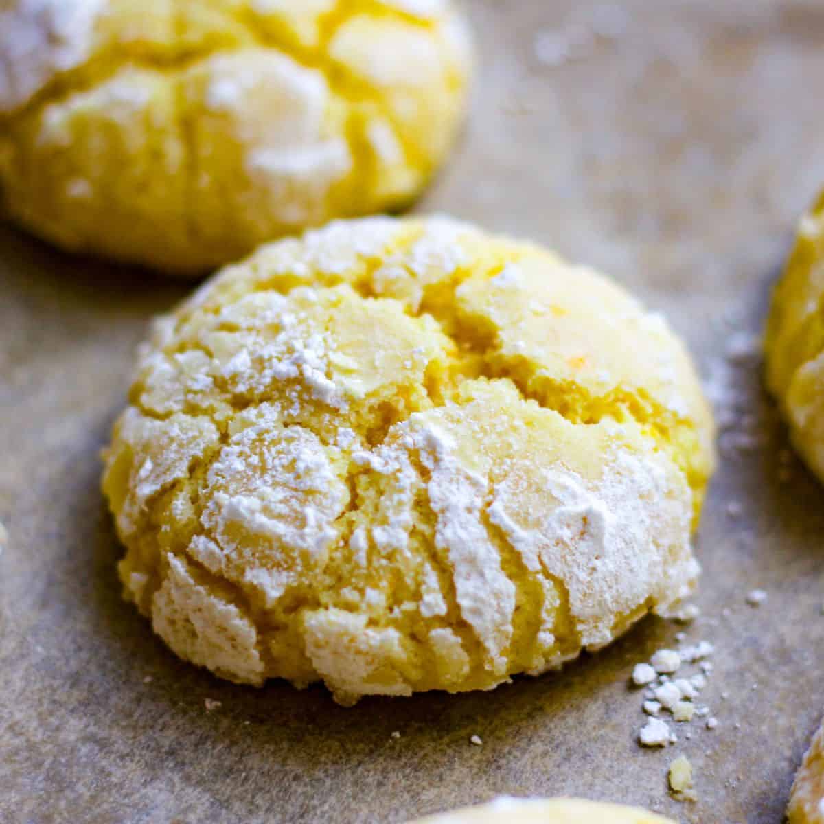 Orange crinkle cookie on a baking pan with crinkled powdered sugar on top.