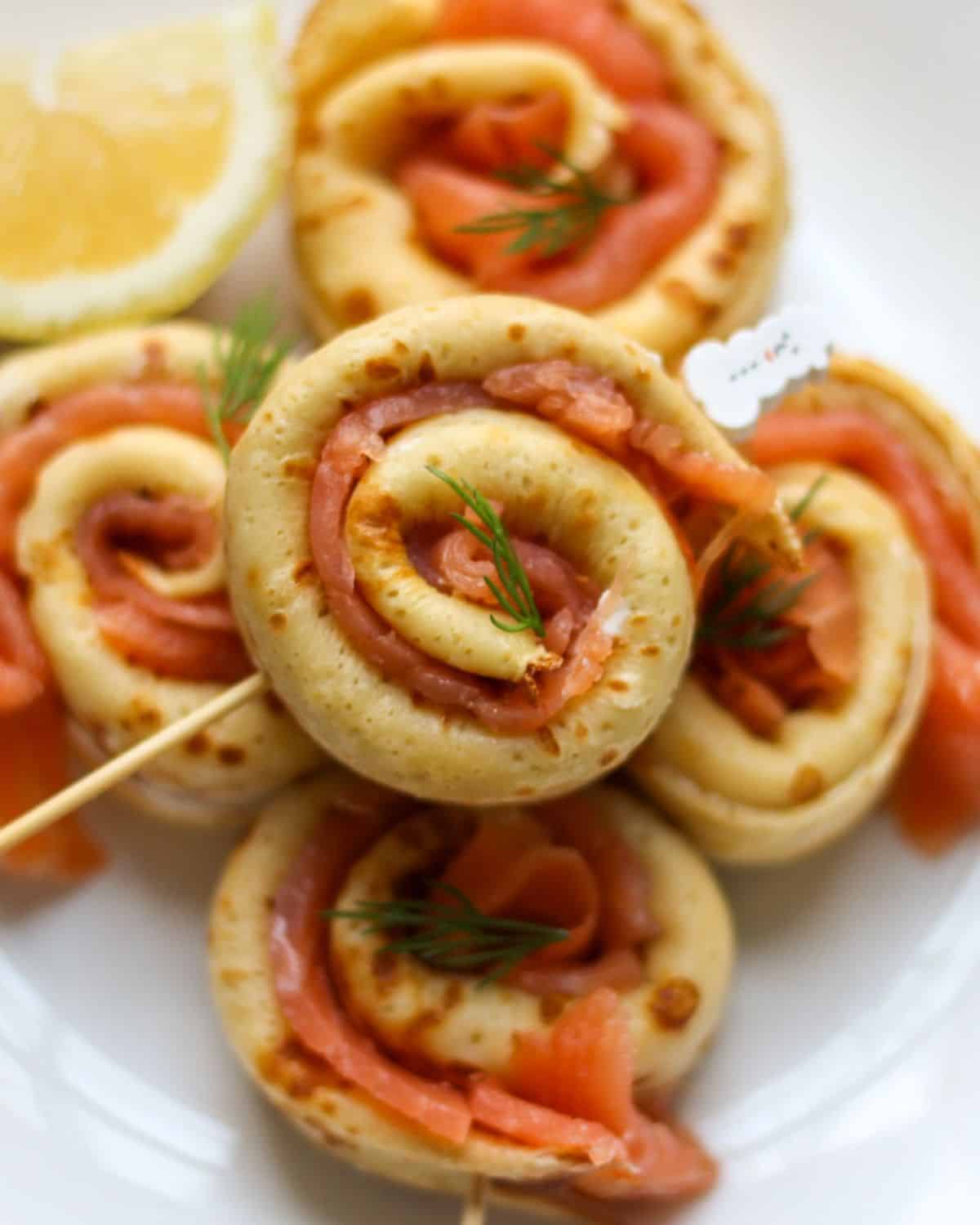 Close-up of smoked salmon crepe roll-ups with creamy filling serves as appetizer.