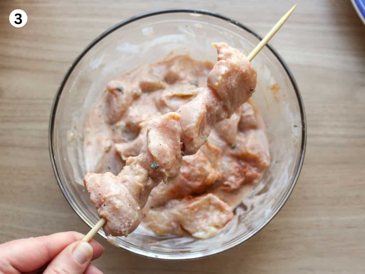 Threading marinated chicken onto wooden skewers. 