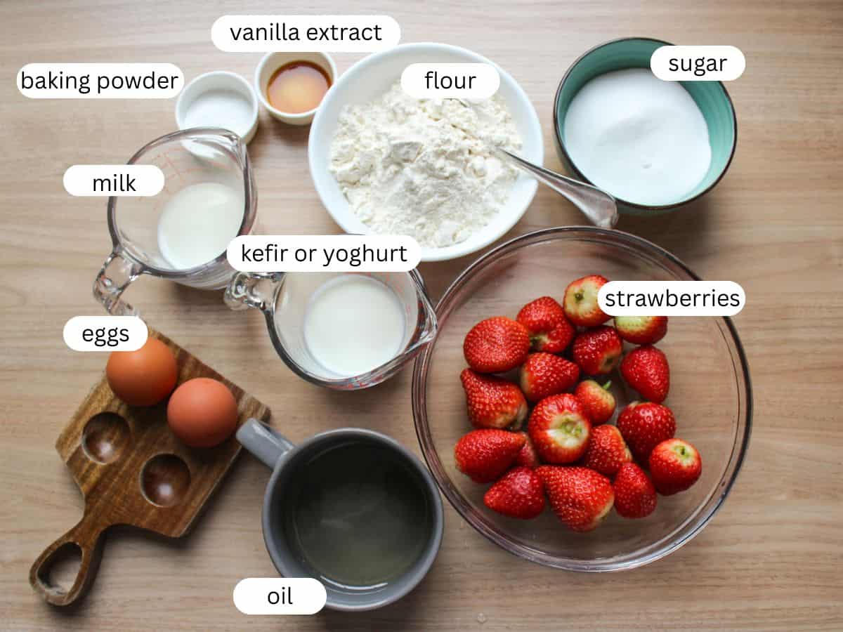 Recipe ingredients on a wooden table for making easy strawberry cake.  