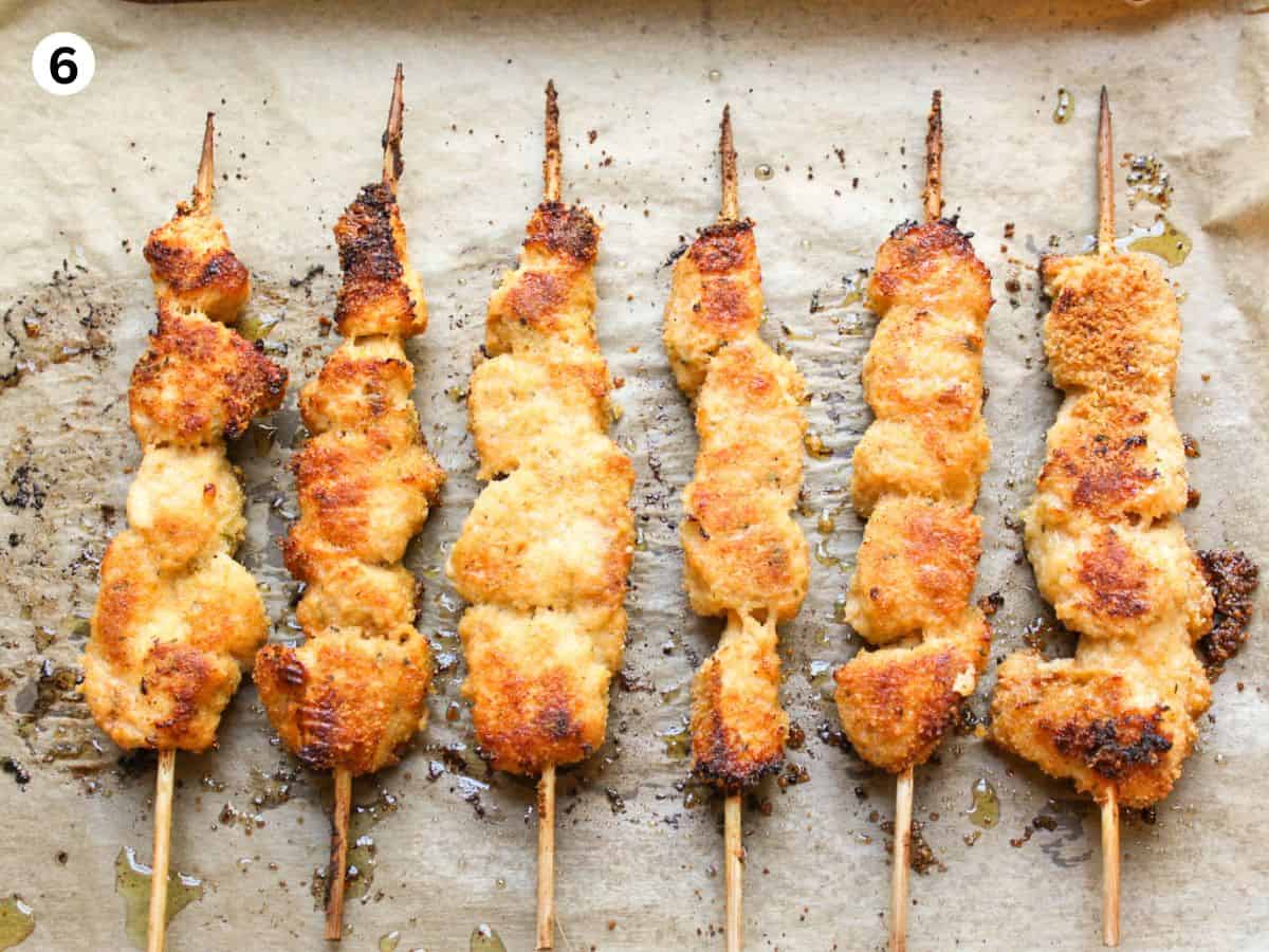 Oven baked garlic Parmesan chicken skewers on a baking pan. 