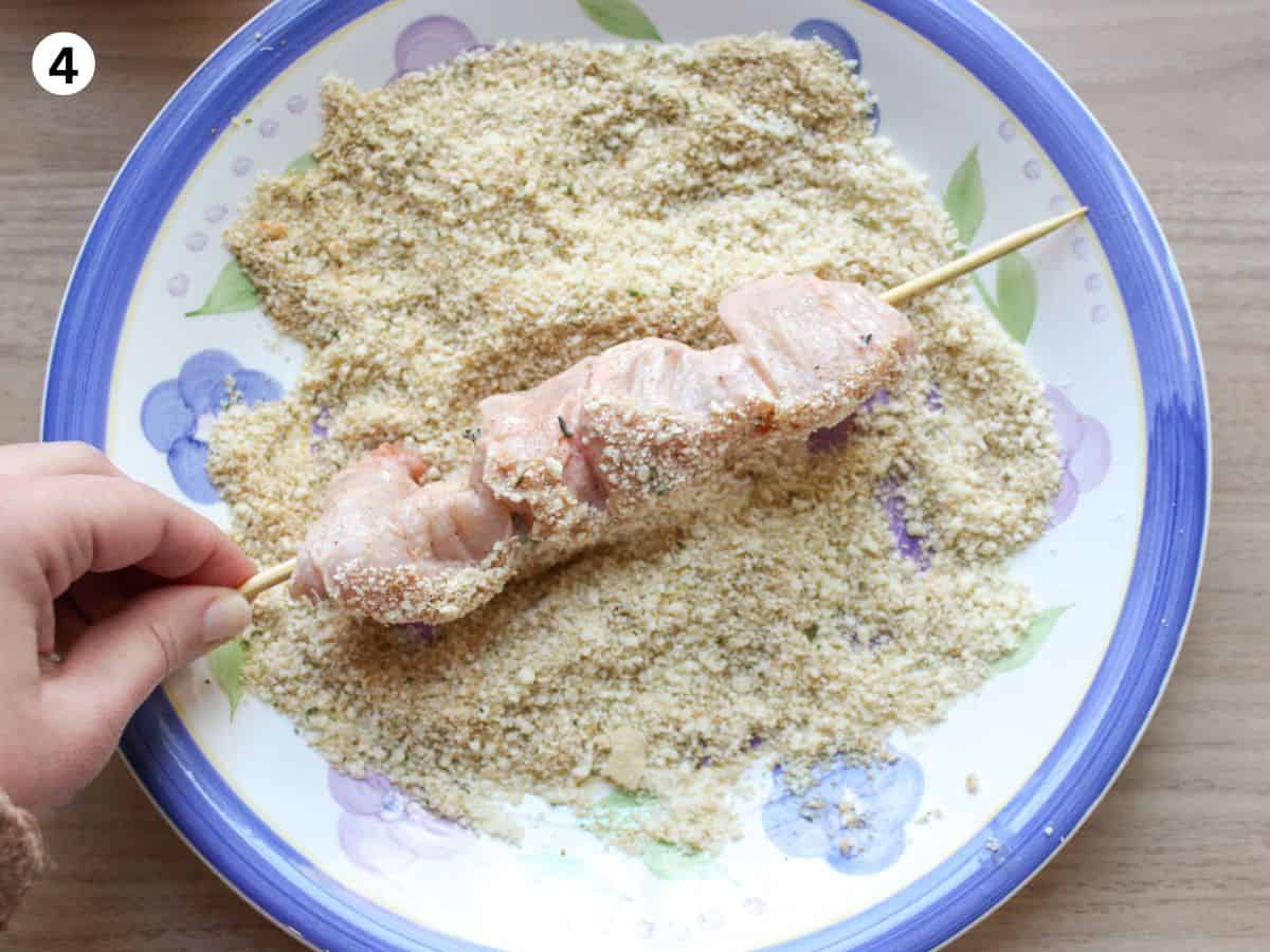 Coating chicken skewers in Parmesan and breadcrumbs. 