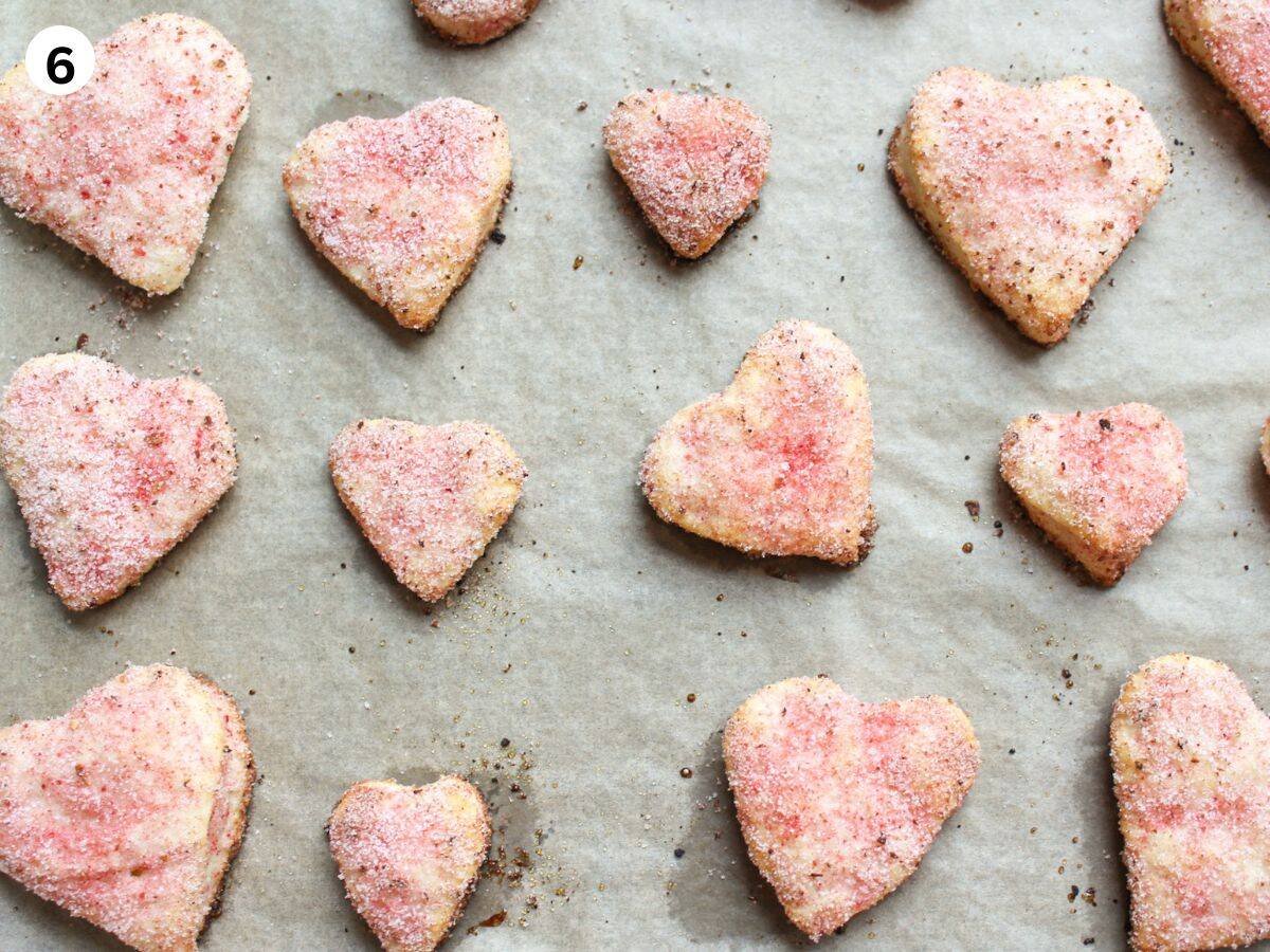 Baked heart shaped soft cookies with strawberry coating on a baking pan, soft centers and crisp edges.  