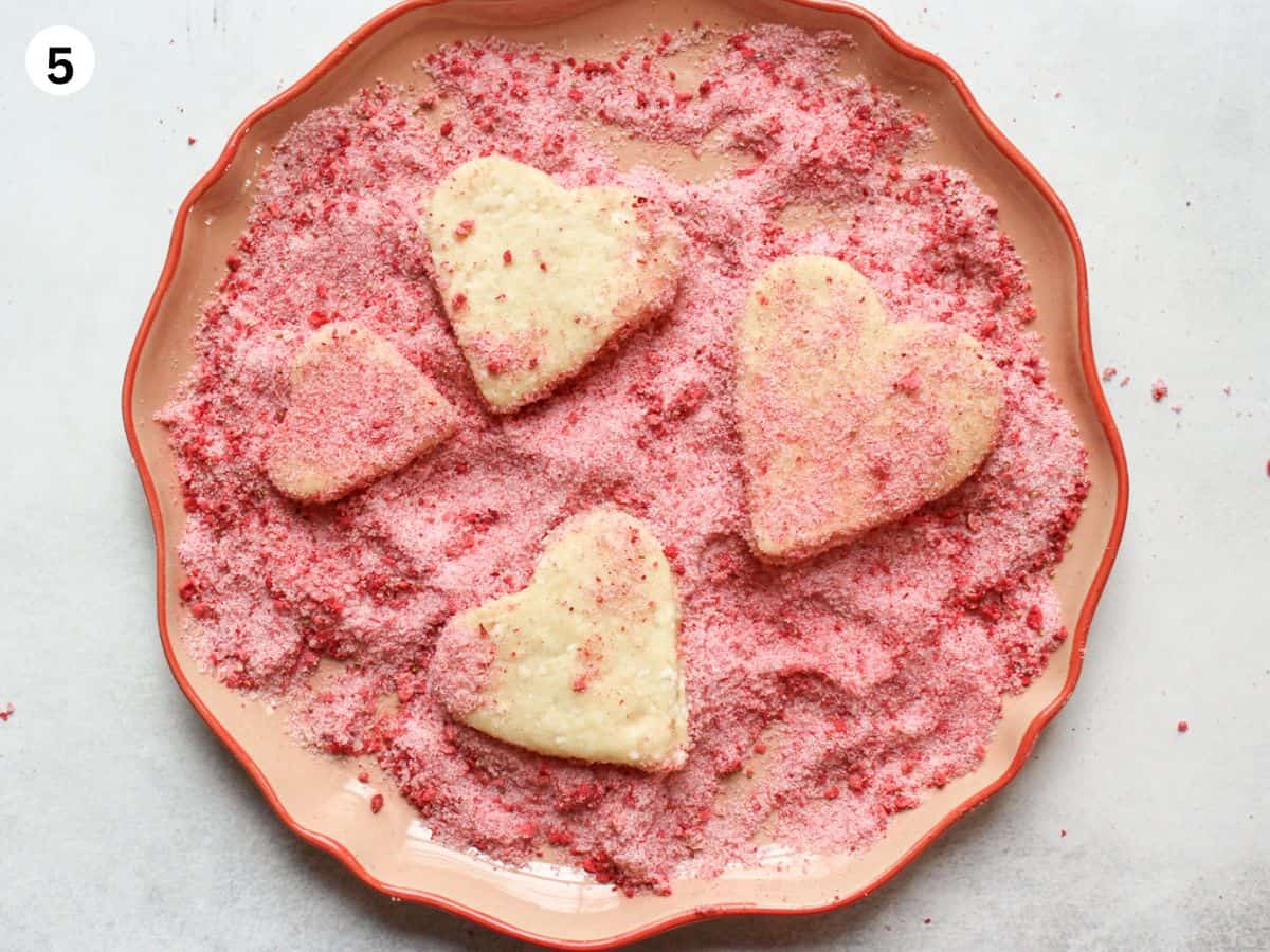 Heart shaped cookies rolled in crushed freeze-dried strawberries before baking.