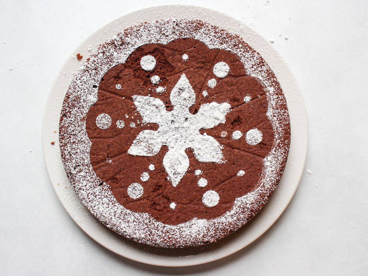 Overhead view of flourless chocolate almond cake dusted with powdered sugar. 