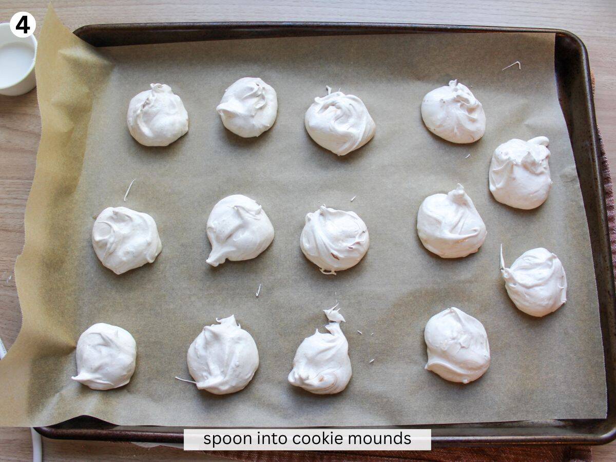 Formed meringue cookies arranged on a baking pan lined with parchment paper. 