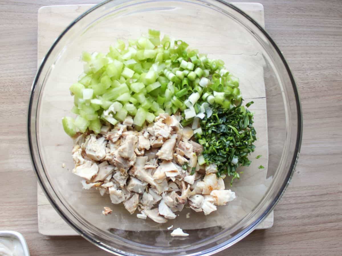 Chopped chicken salad ingredients added to the large glass bowl. 