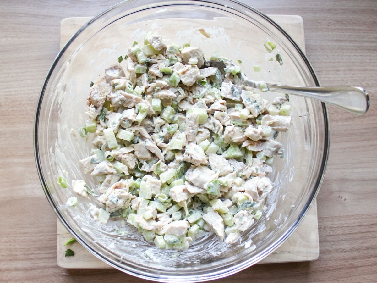 Classic chicken salad mixed with the creamy dressing in a glass bowl. 