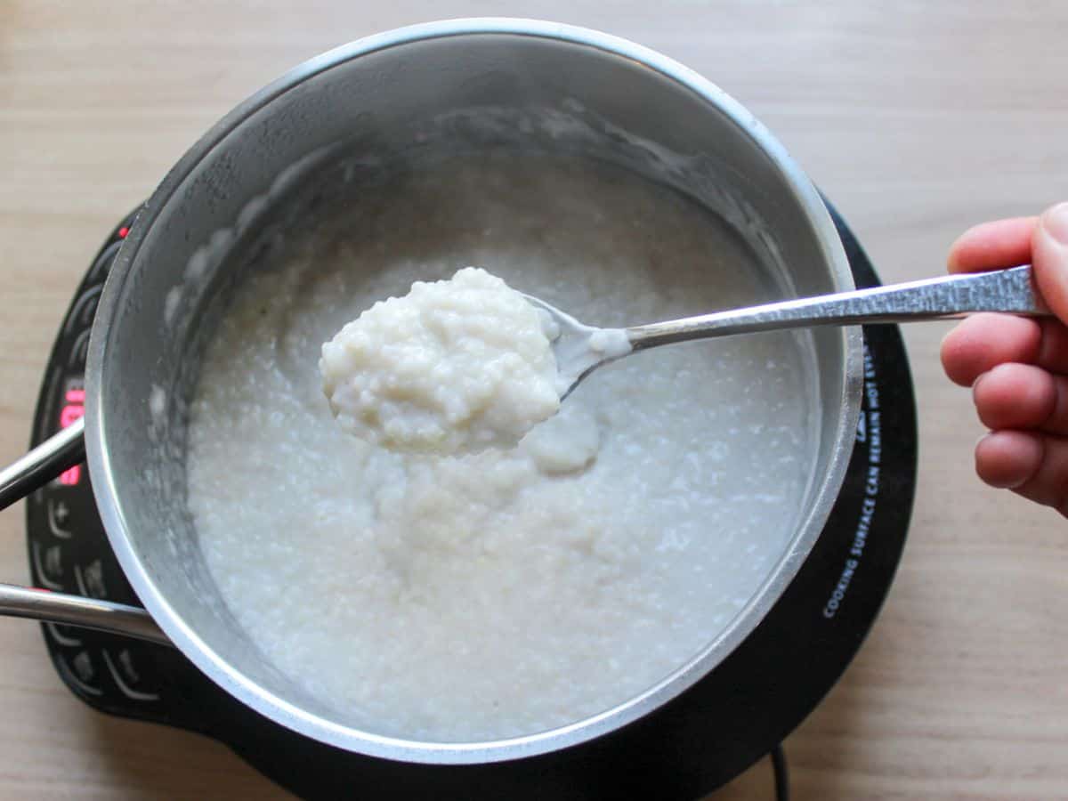 Cream of buckwheat porridge cooked in a saucepan, with a spoon lifting a portion.