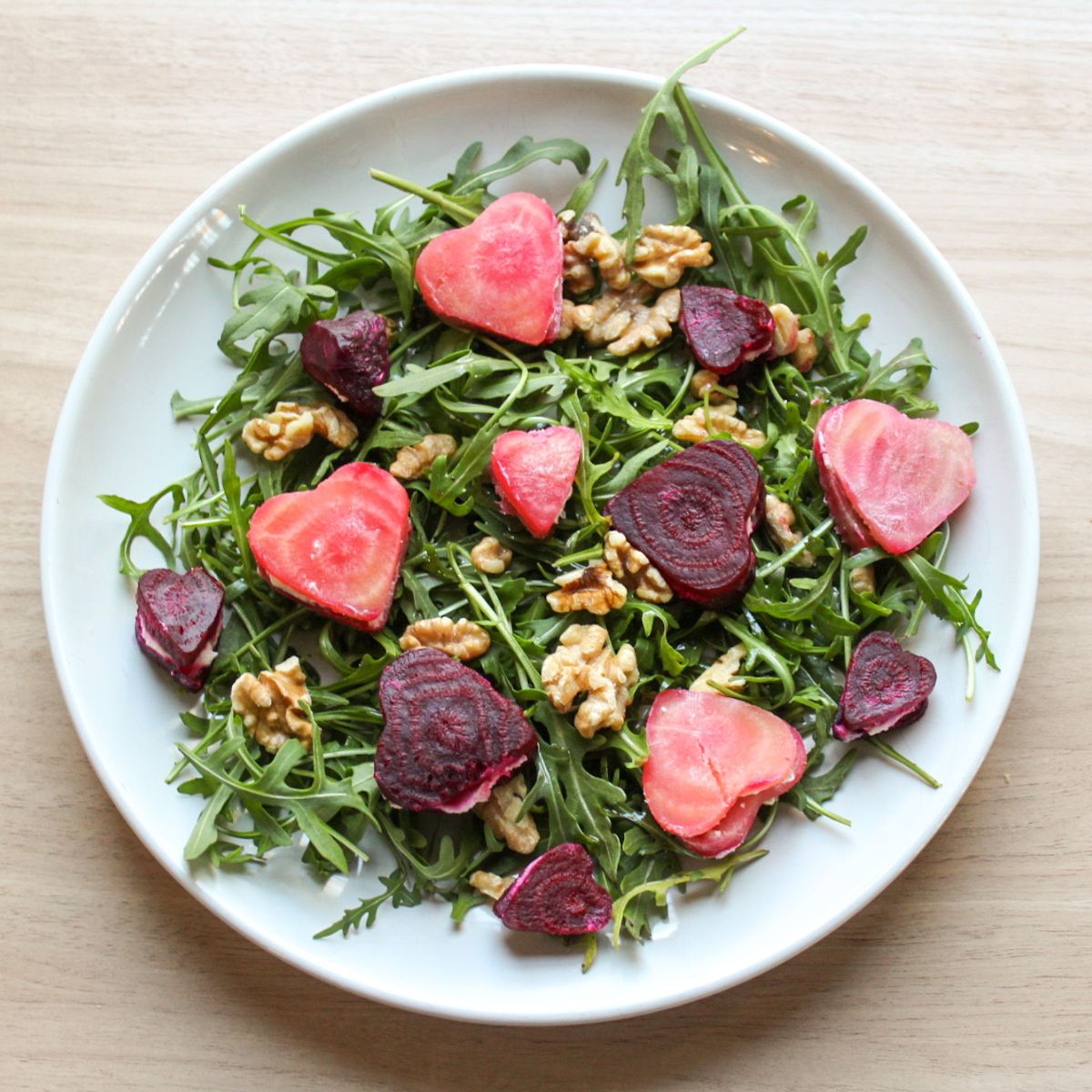 Valentine's Day salad made with arugula, goat cheese, walnuts and beets served on a large salad platter.