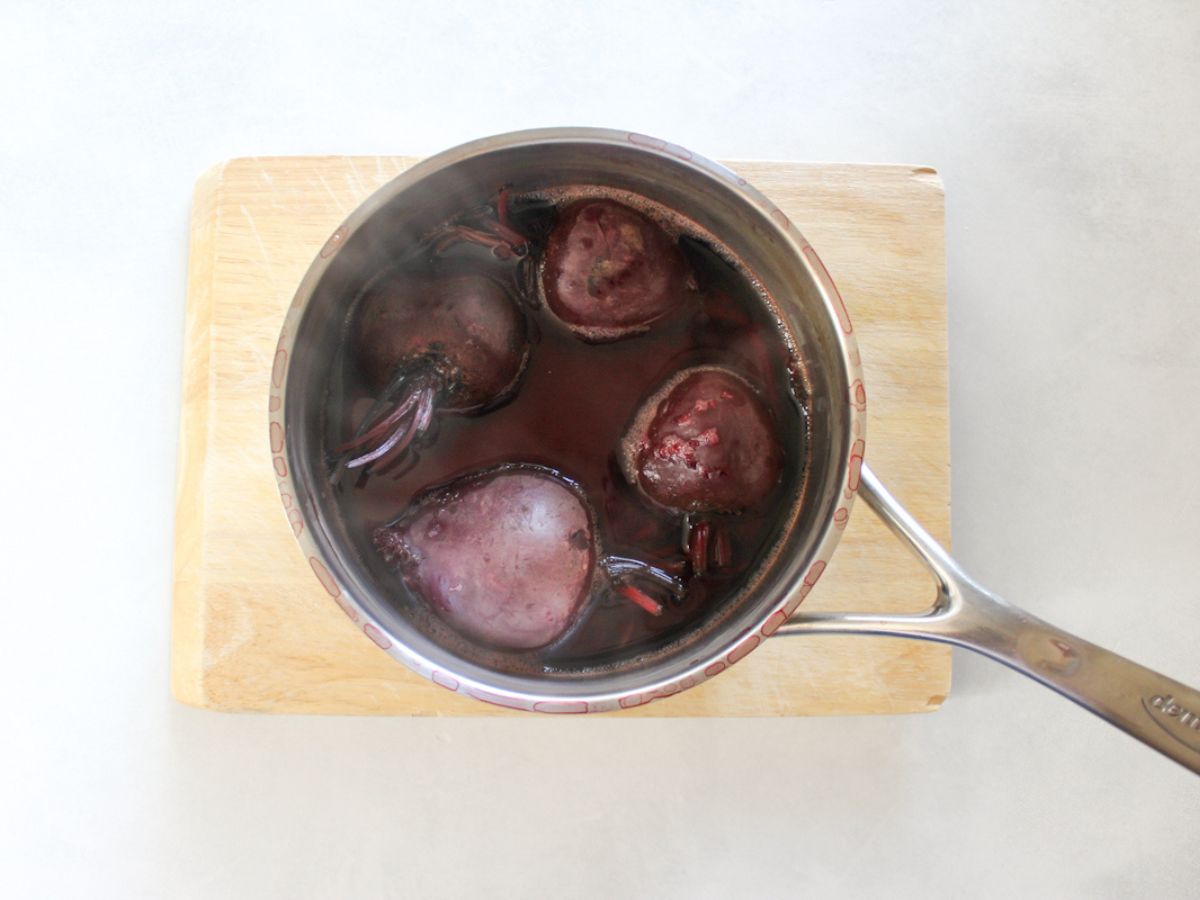 Boiled whole beets in a large pot. 