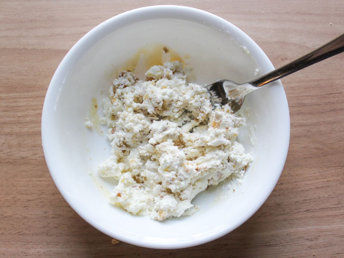 Mixing goat cheese with chopped walnuts and honey. 