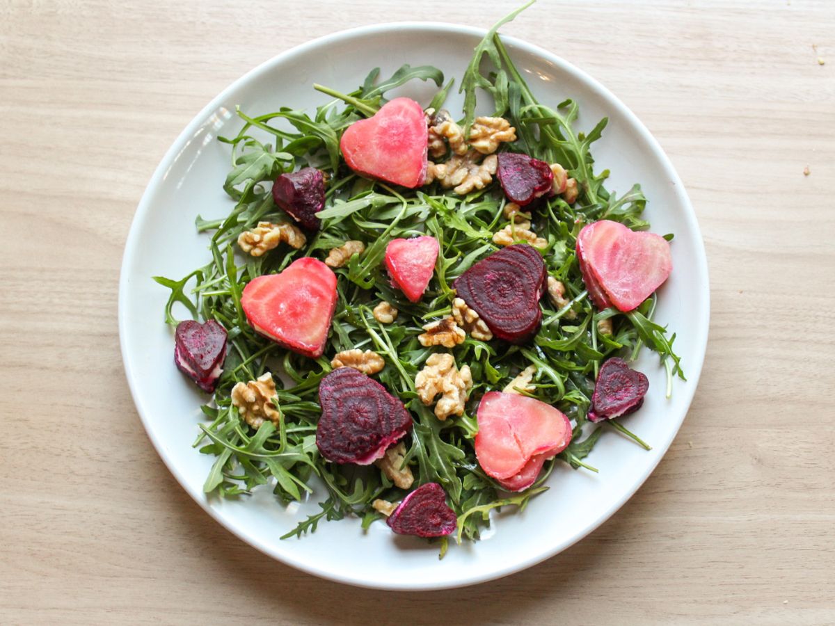 Valentine's Day salad made with arugula, goat cheese and beets served on a large salad platter. 