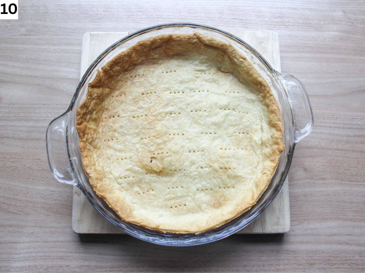 Baked tart crust in a 9-inch round pan placed on a cutting board.