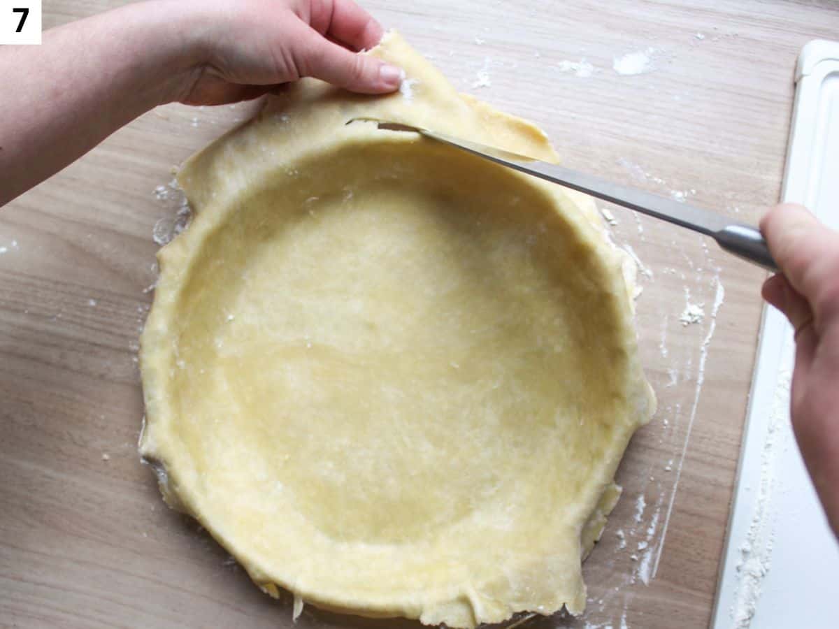 The dough added to the round pan and trimmed with a knife.