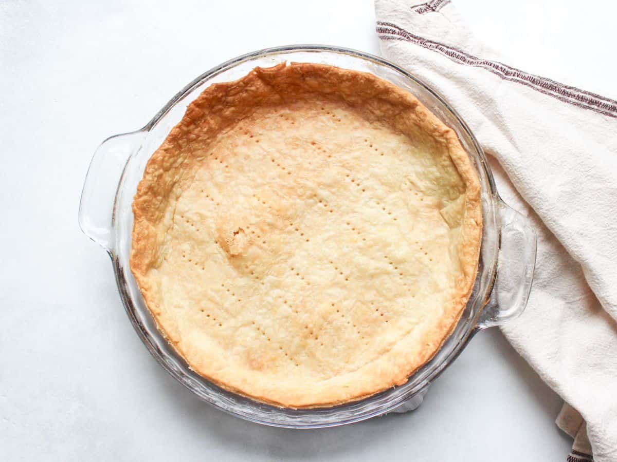 Buttery, flaky pâte brisée tart crust in a 9-inch baking pan, ready for savory or sweet fillings. 