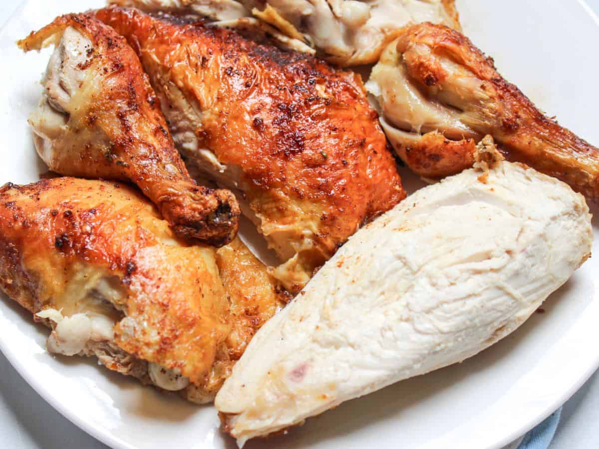 Pieces of roasted chicken with crispy skin served on a large plate.