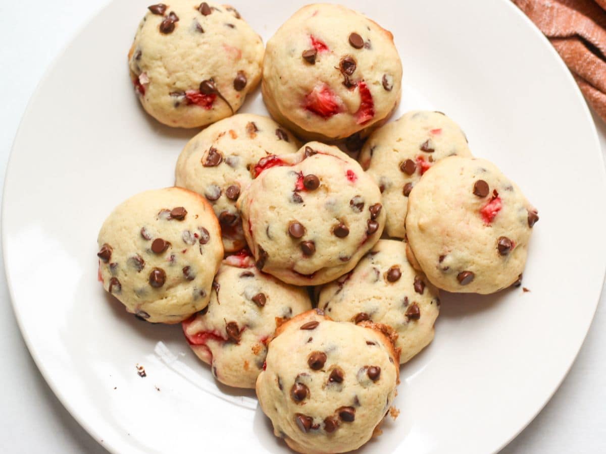 Soft chocolate chip cookies with fresh strawberry pieces served on a plate.