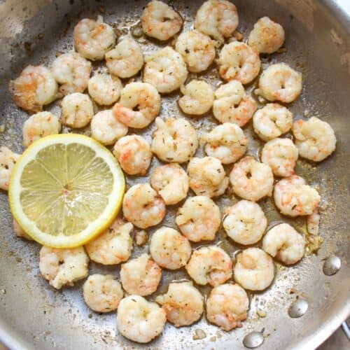 Pan-fried shrimp cooked in a skillet with garlic butter and lemon.